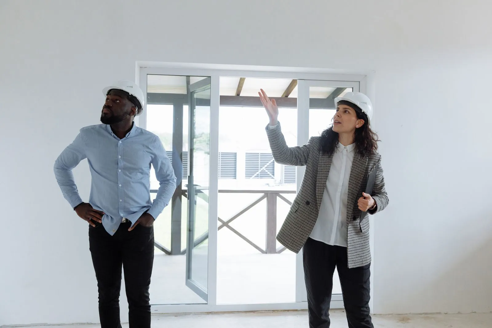 Una mujer con casco recorre con un colega una casa en construcción y le señala detalles
